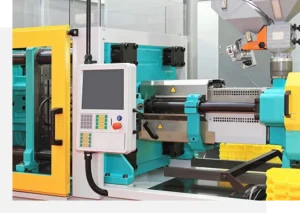 A modern injection molding machine with a control panel. The machine features yellow safety guards and metallic components, designed for precise manufacturing processes.