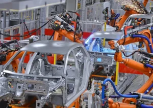 Robotic arms assemble car frames on an automated production line in a factory.