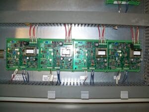 A series of green printed circuit boards (PCBs) mounted in a metal casing, with various electronic components and connected wires.