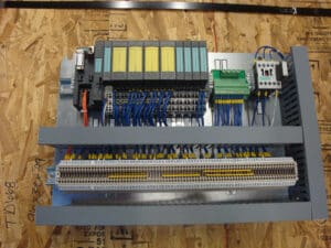 A wiring panel with various connectors, relays, and cables is mounted on a wooden surface labeled TD6 - 08. Blue and yellow wires are connected to different terminal blocks.